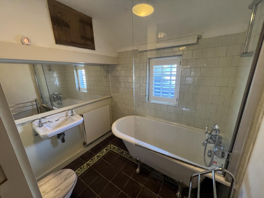Lot: 138 - TWO-BEDROOM THATCHED COTTAGE FOR OCCUPATION OR INVESTMENT - Bathroom with roll top bath and white wall tiles